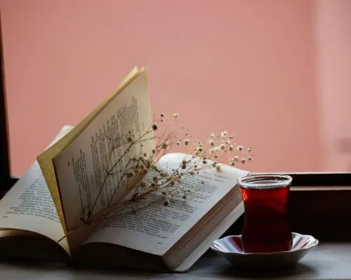 Livre ouvert, fleurs séchées et tasse de thé près d'une fenêtre