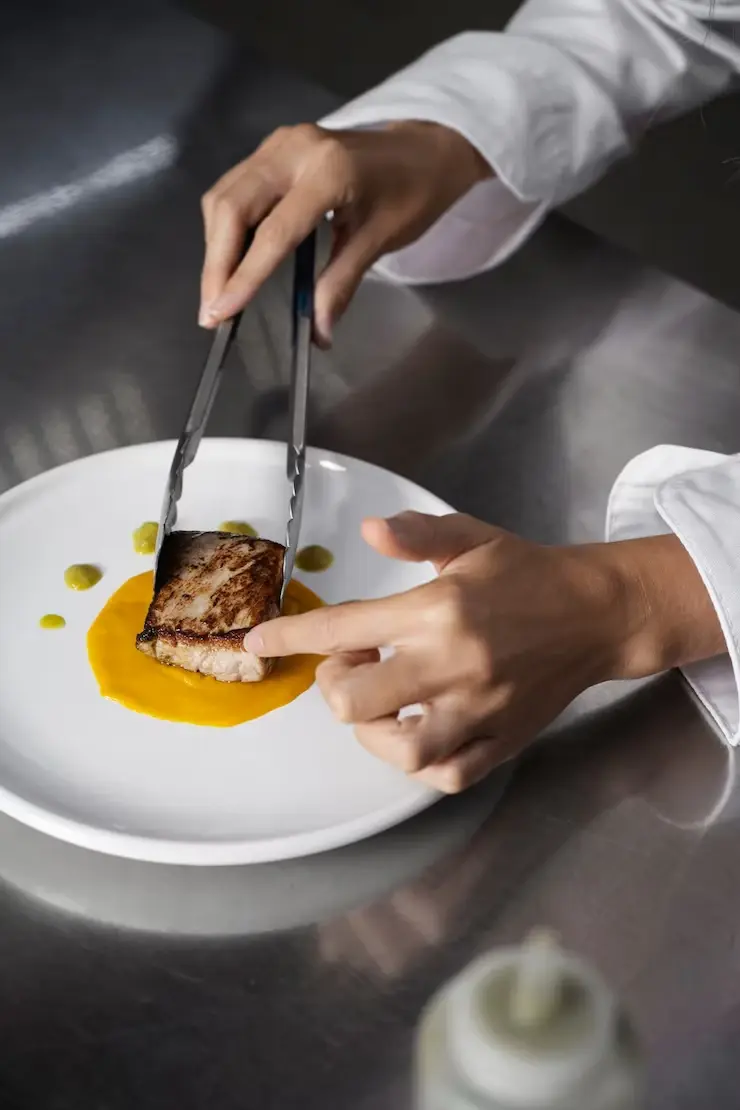 Cheffe dressant une assiette dans une cuisine professionnelle