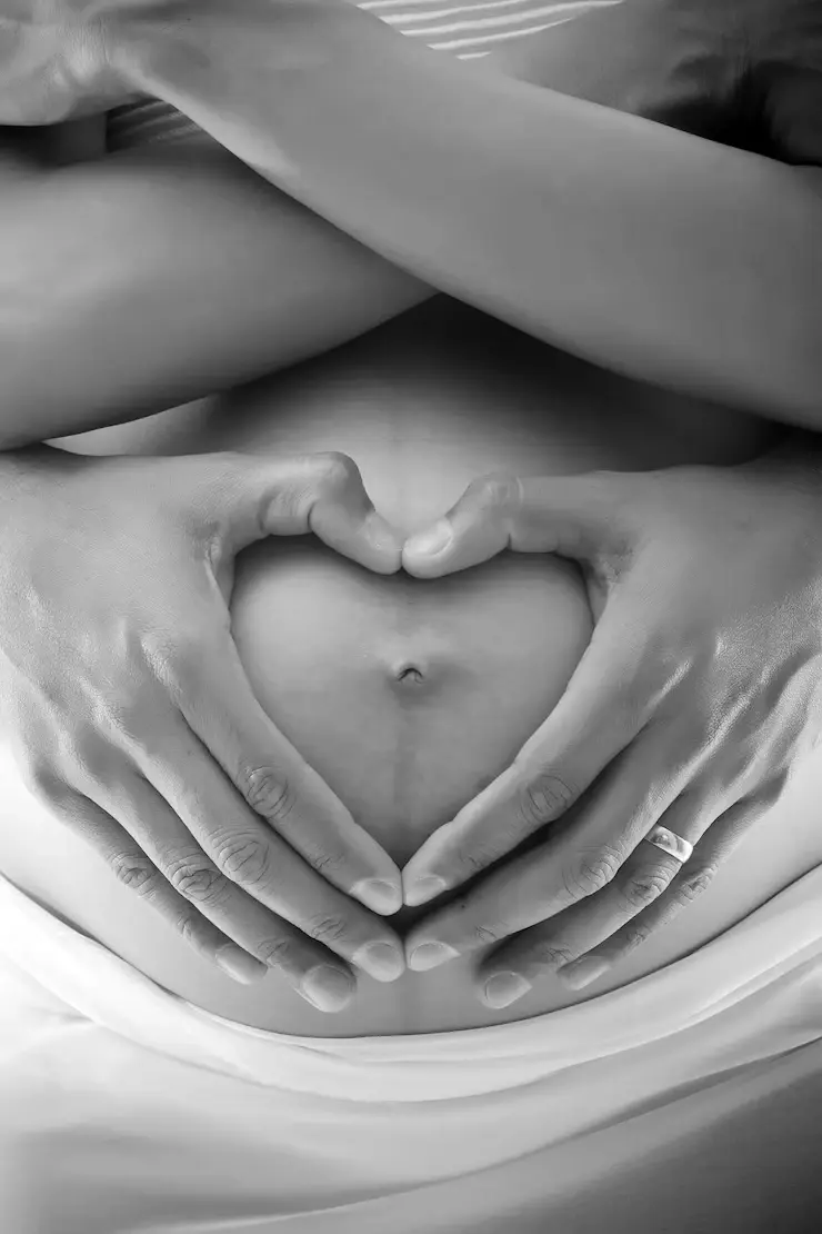 Mains formant un cœur sur le ventre d’une femme enceinte