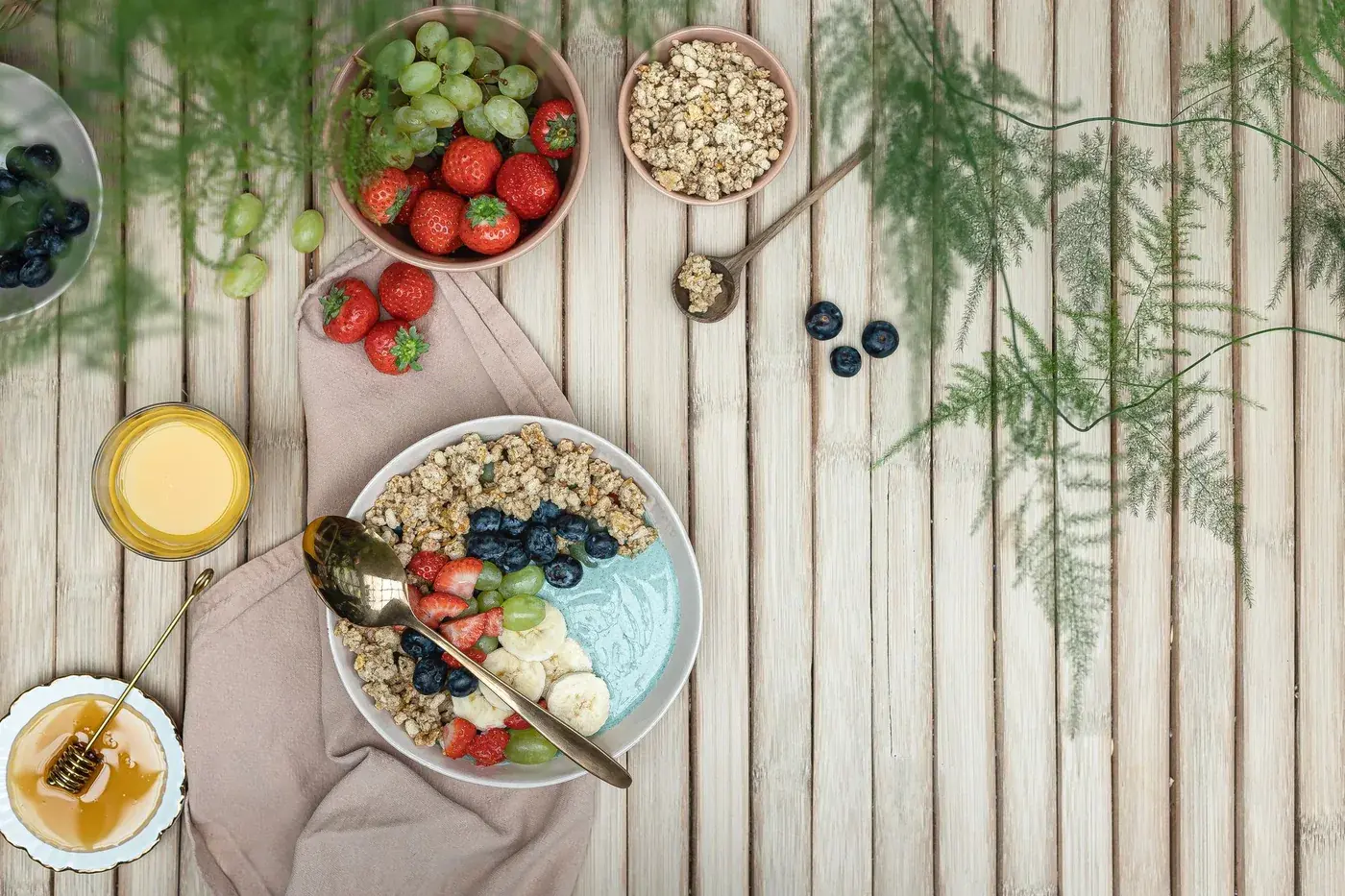Petit-déjeuner équilibré sur une table en bois : bols de fruits frais, granola et jus d’orange