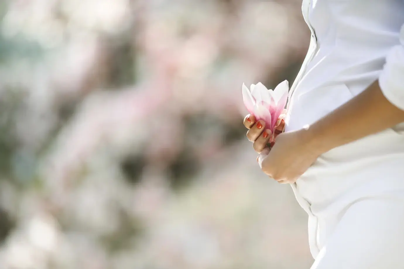 Femme enceinte tenant une fleur de magnolia contre son ventre