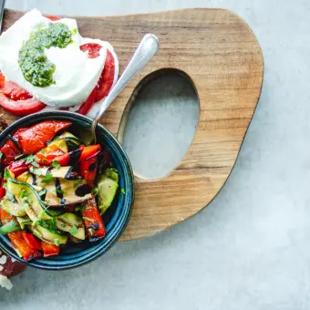 Assiette de légumes grillés, mozzarella, tomates et saumon sur une planche en bois